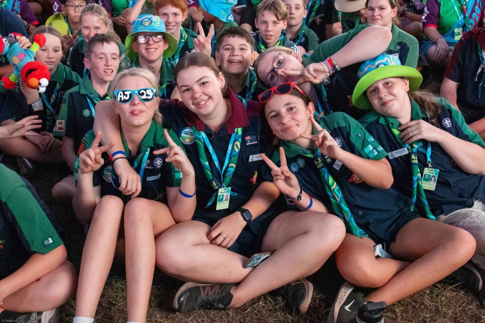 Scouts sitting together on the grass giving peace signs